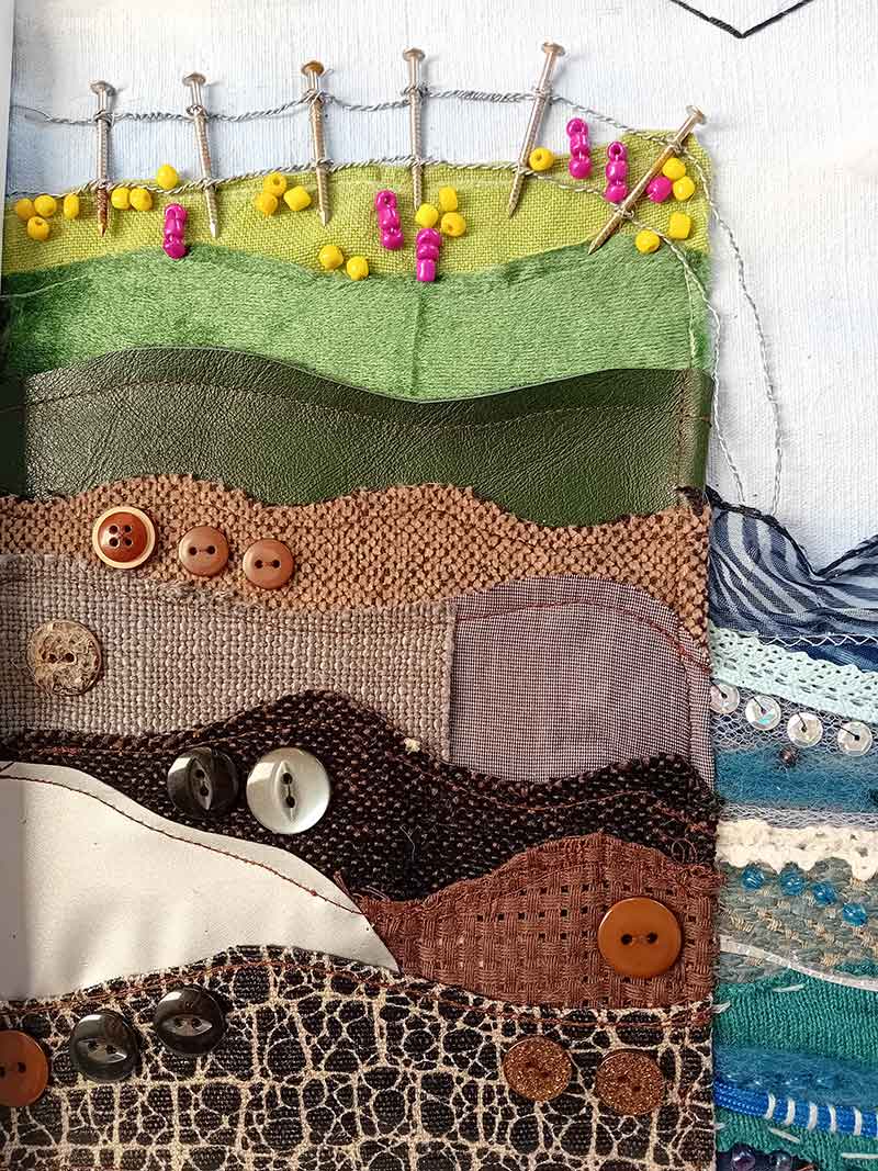 A mixed-media textile piece inspired by the colours and textures along the Wales Coast Path. I have used beads, sequins, buttons and ribbons in the cliff and the sea to demonstrate the different patterns and textures that stood out the me the most. By incorporating layers of brown fabric on the cliff, coupled with nails and wire to create the effect of the fence falling away into the sea, I hope to highlight the sea’s power both to erode the landscape and uplift mental wellbeing.